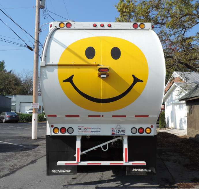 back of an ADS garbage truck with the giant yellow smiley face on the back