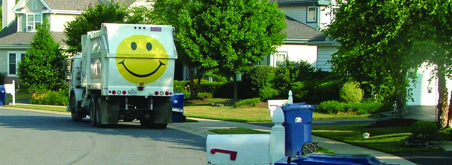 ads trash truck in a residential neighborhood on a sunny day